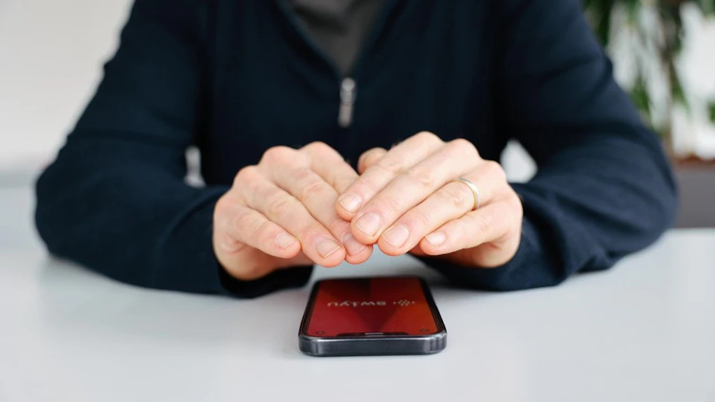 Zwei Hände über einem Mobiltelefon